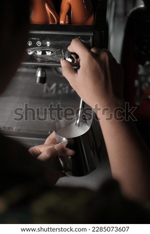 barista steaming milk at an espresso machine in a cafe