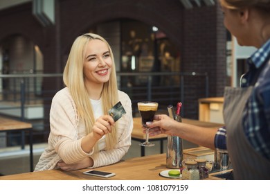 Barista taking credit card from customer to pay for beverage at coffee shop counter. Small business, occupation people, payment and service concept, copy space