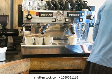 Barista using a coffee maker and prepares cup of coffee for a customer - Shutterstock ID 1089331166