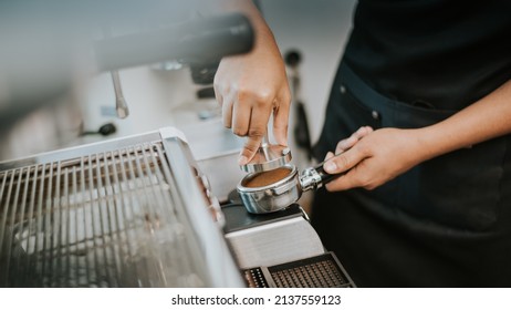 Barista using a tamper to press ground coffee into a portafilter. Close-up view on barista hands to making coffee with coffee machine. Coffee owner concept. - Powered by Shutterstock