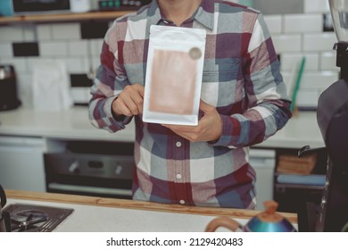 Barista wearing plaid shirt holding coffee pack - Powered by Shutterstock