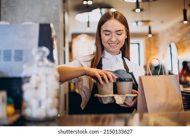 Barista woman at coffee shop preparing coffee in cardboard cups - Powered by Shutterstock