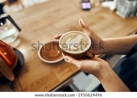 Barista woman giving order to client at the trendy coffee shop. Coffee cup with latte art