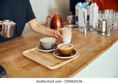 Barista woman making cappuccino here in cups and to go, female preparing coffee drink. Coffee cup with latte art