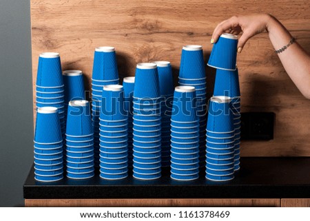 barista woman takes a paper glass, many mills in a pile