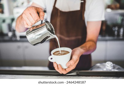 Barista working in coffee shop, preparing latte, making cappuccino. Bartender in apron preparing coffee drink. - Powered by Shutterstock