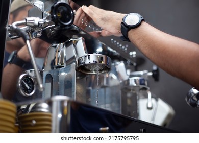 Barista's hands clean the filter by running hot water from the group head on the coffee machine. - Powered by Shutterstock