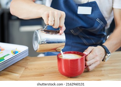 Barista's Hands Pouring Milk Into A Cup Of Cappuccino