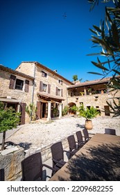 Barjac, France - July 24th 2022 : Beautiful Large Provencal Villa From The South Of France In Europe With Its Light Stone Walls, Gravel, Shrubs, Blue Sky And Olive Leaves Sticking Out Of The Top