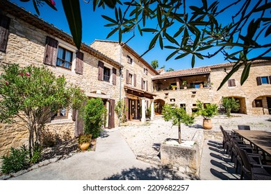 Barjac, France - July 24th 2022 : Beautiful Large Provencal Villa From The South Of France In Europe With Its Light Stone Walls, Gravel, Shrubs, Blue Sky And Olive Leaves Sticking Out Of The Top