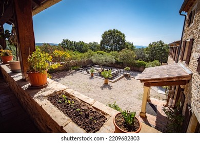 Barjac, France - July 24th 2022 : View On A Private Provençal Garden In The South Of France From A Balcony Of The Large Stone Villa With Gravel, Olive Trees, Shrubs And A Terrace With Wooden Tables