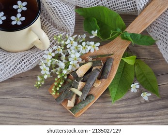 Bark and twigs of bird cherry with white flowers, herbal tea on a wooden table, flat layout. Seasonal plant Prunus padus for use in food, alternative medicine, homeopathy and cosmetology - Shutterstock ID 2135027129