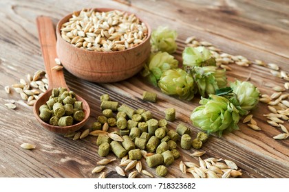 Barley in a wooden bowl, fresh and granulated hop in a spoon on a wooden table. Concept for craft beer and brewing