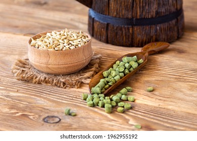 Barley in a wooden bowl, granulated hop in a spoon on a rustic table. Concept for craft beer and brewing