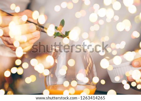 Barman decorating  cocktail at a nightclub. Nightlife and entertainment concept. Horizontal, bold light bokeh
