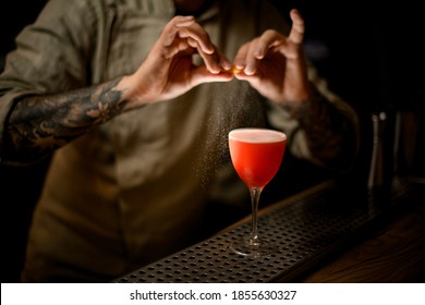 Barman Gently Holds Lemon Peel In His Hands And Sprinkles On Glass With Bright Cocktail.