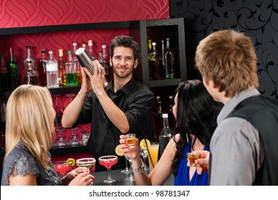 Barman making cocktail for young friends at the bar