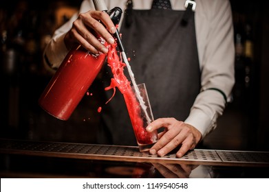 Barman Pouring Alcoholic Sparkling Water Into A Sweet Red Berry Summer Cocktail On The Bar Counter