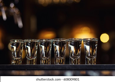 Barman pouring hard spirit into small glasses such as alcoholic shots of tequila or strong drink - Powered by Shutterstock