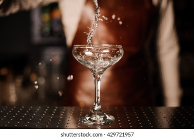 Barman Pouring Into Champagne Glass And Making A Splash