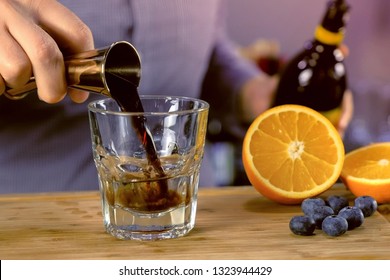 Barman Pours Kahlua From Jigger To Rocks Glass With Tequila Preparing Alcohol Cocktail. Hands Close-up.