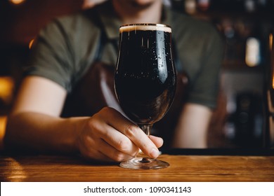 Barman serves glass of dark cold beer at bar counter. - Powered by Shutterstock