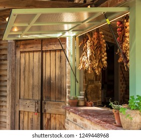 Barn Door Closed But With A Louvered Window Open To A Farm Kitchen With Onions And Garlic Hanging In The Corners