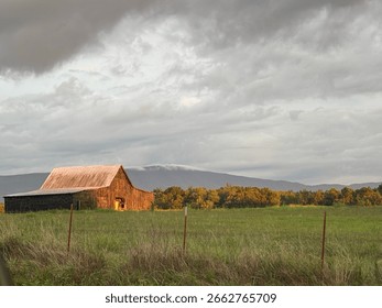A barn in front of the mountains