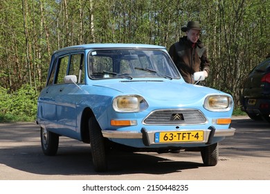 Barneveld, The Netherlands - April 2022: Blue Vintage Citroën Ami Car With Young Man Standing Next To It Against Natural Background With Trees