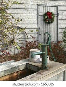 Barnyard With Christmas Wreath On White Barn, Wagon Wheel And Water Pump