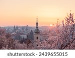 Baroque chapel bell tower steeple at historical part of city on the background of an orange red sunrise sky.