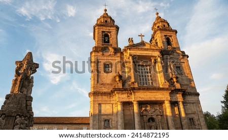 Baroque church towers soar above urban streets, framed by historic buildings under the golden light of an early evening in a European city.