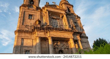Baroque church towers soar above urban streets, framed by historic buildings under the golden light of an early evening in a European city.