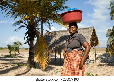 BARRA, MOZAMBIQUE - JUNE 13, 2015: Unidentified woman has different goods in a bowl and carries it on her head traditionally and sells it at the beach in Barra.