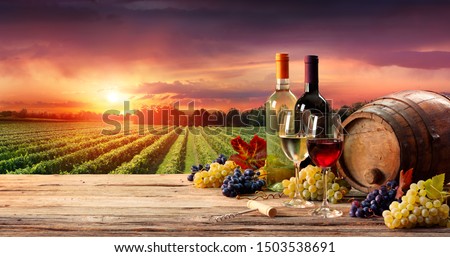 Barrel Wineglasses And Bottle In Vineyard At Sunset
