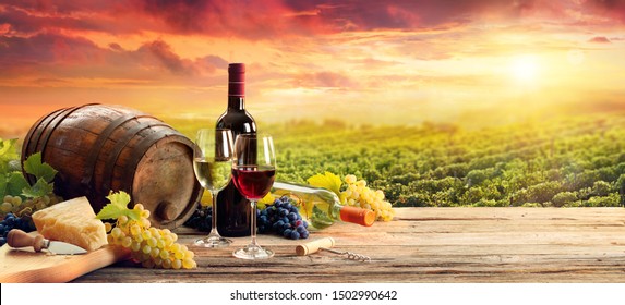 Barrel Wineglasses Cheese And Bottle In Vineyard At Sunset
