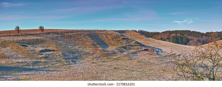 Barren Desert Hills With Trees. Empty Sandy Mountain Landscape With A Pine Forest In The Background. Serene Nature Scene With No People. Lifeless Mountainside In Spring Against A Bright Blue Sky