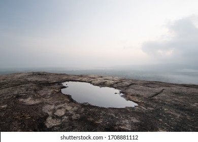 Barren rock and puddle. Panorama shot of the sunrise sky and its reflection in a puddle of water, from the vantage point of Pidurangala rock, next to the famous Sigiriya Lion Rock in Sri Lanka.