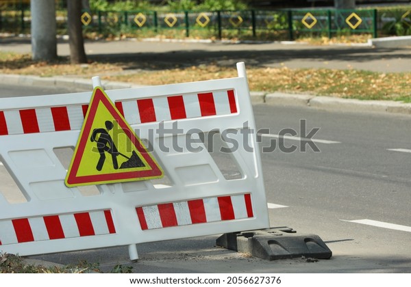 Barricade with road construction sign on city\
street. Repair works