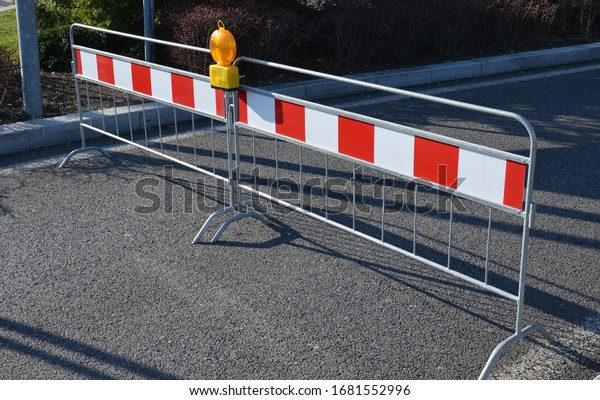 barrier against traffic entrance or traffic\
control portable with orange flashing reflector red-white stripes\
railing galvanized on the road side\
view
