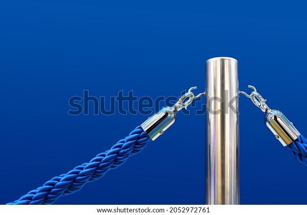 Barrier fence,\
velvet and metal racks. Close-up of a portable barrier with a blue\
rope against a blue\
background.