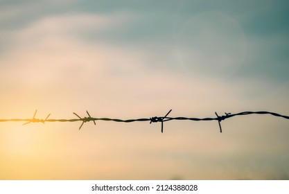 Barrier wire fence with sunset Twilight sky. Chain spike for world war safe security boundary concept for human rights slave, prison hostage hope to peace. International liberty day. russia ukraine