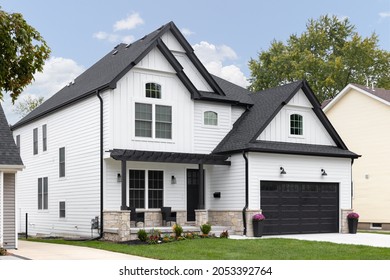 BARRINGTON, IL, USA - OCTOBER 5, 2021: A Traditional Modern Farmhouse With White Siding, Black Roof And Garage Door, And A Covered Front Porch.