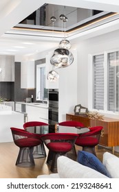 BARRINGTON, IL, USA - SEPTEMBER 25, 2021: A Luxurious, Contemporary Dining Room With A Red Tables Around A Circular Table And A Modern Light Fixture Hanging Above.