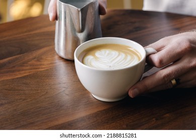 Barrista Holding Latte On Table 