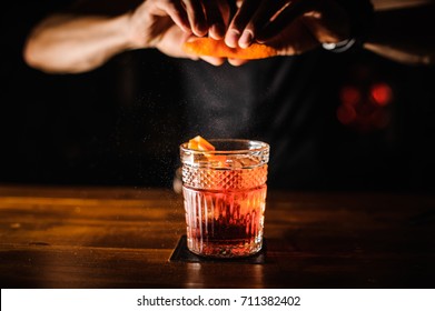 bartender with cocktail and orange peel preparing cocktail at bar. alcohol drinks, people and luxury concept - Powered by Shutterstock