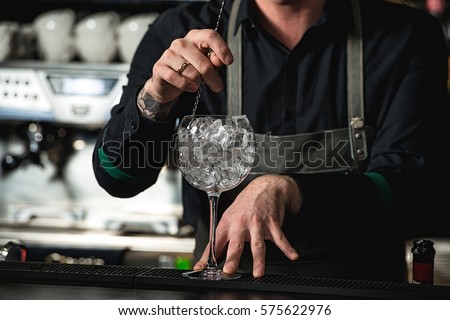 Bartender cooling out Cocktail glass mixing ice with a spoon