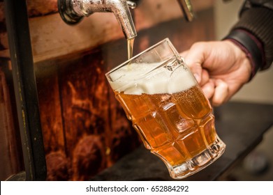 Bartender filling up with a blonde craft beer into a pint glass