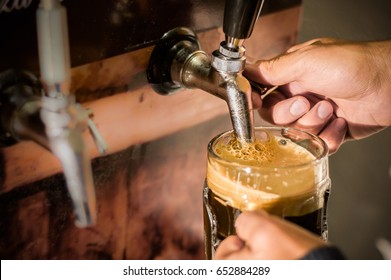 Bartender filling up with craft beer a pint glass