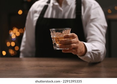 Bartender with glass of whiskey at bar counter indoors, closeup - Powered by Shutterstock